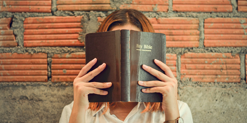 Lady with bible in front of face