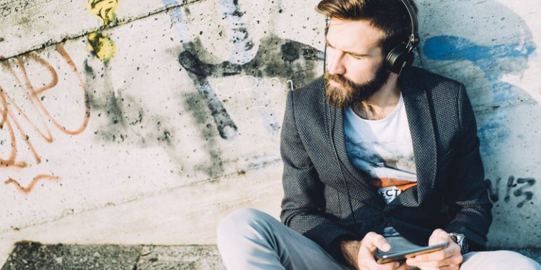 Man listening on headphones holding a tablet